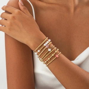 Détail de bracelets bohèmes dorés multicouches avec perles et breloques en croix