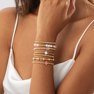 Gros plan sur des bracelets bohèmes superposés avec perles et breloques en croix