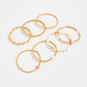 Vue détaillée de bracelets de perles dorées bohèmes avec perles et breloques croix