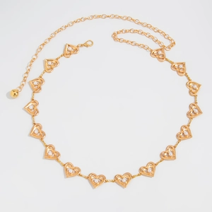 Detail of golden heart-shaped metal waist chain with elegant white pearl accents