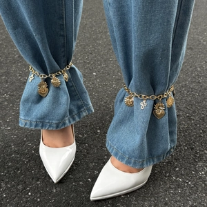 Cavigliera vintage dorata con ciondoli a croce e cuore sacro su jeans in denim
