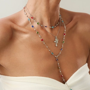 Dettaglio di collane a strati in argento con cristalli colorati e ciondolo a croce retro