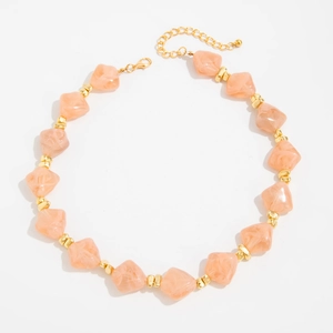 Detailed close-up of peach resin beads necklace with gold spacers and lobster clasp