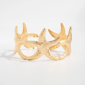 Detail van een gouden zeester bovenarmband met gehamerde metalen textuur en oceaanstijl