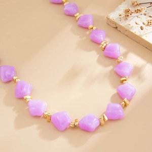 Detail view of purple irregular resin beads and gold metallic spacers on a beaded necklace