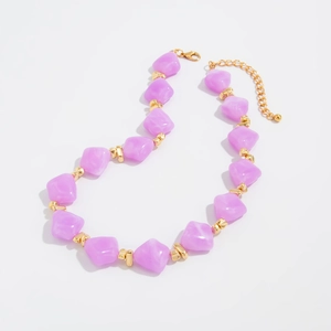 Detail of purple resin beads with marble texture and golden spacers on a choker necklace