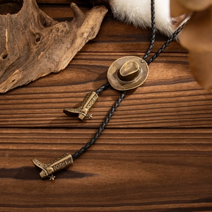 Detail einer Western-Bolo-Krawatte mit bronzenem Cowboyhut-Schieber und Stiefel-Anhängern
