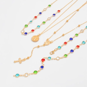 Dettagli di collane placcate in oro con cristalli colorati e ciondoli a croce