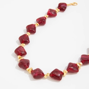 Close-up of burgundy irregular resin beads with gold spacers and lobster clasp