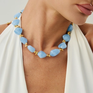 Close-up of irregular light blue resin beads and golden metal spacers on a choker