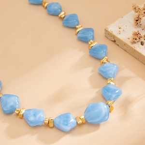 Detail of blue irregular resin beads and gold metallic spacers on a beaded choker necklace