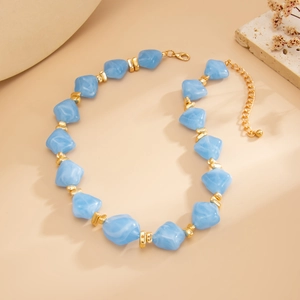 Close-up of irregular blue resin beads necklace with gold metal spacers and lobster clasp