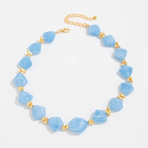 Detail of light blue irregular resin beads with golden spacers and lobster clasp necklace