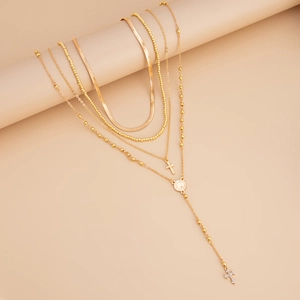 Detalle de collares dorados en capas con cadena de serpiente y colgante de cruz