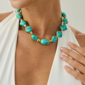 Close-up of irregular turquoise resin beaded necklace with golden cube spacers for women