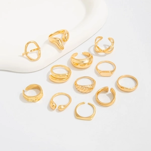 Vue à plat d'un ensemble de 12 bagues dorées irrégulières style lave sur fond blanc