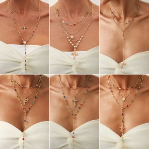 Collana multistrato dorata con cristalli colorati e ciondolo a croce su modella