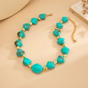 Close-up of turquoise irregular beads and gold lobster clasp on beaded necklace