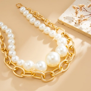 Collana a doppio strato con catena dorata e perle sfumate su uno sfondo materico