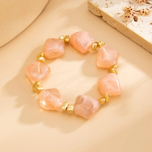 Detail of pink marble resin beads and golden spacers on an irregular beaded necklace