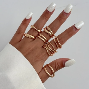 Détail de bagues dorées irrégulières style lave liquide portées avec chemise blanche