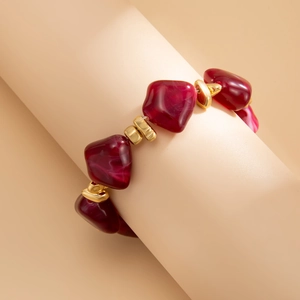 Detail of irregular dark red resin beads with gold spacer beads on a wrist display