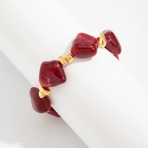 Macro detail of irregular burgundy resin beads and golden metallic accents on a choker necklace