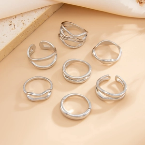 Mise à plat de sept bagues en métal liquide argenté aux designs ouverts minimalistes