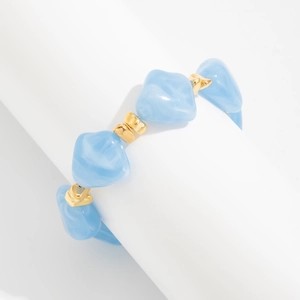 Macro detail of blue irregular resin beads and gold accents on a beaded choker necklace