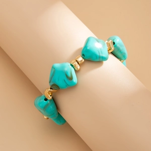 Macro shot of irregular turquoise resin beads and golden metal spacers on a beaded choker
