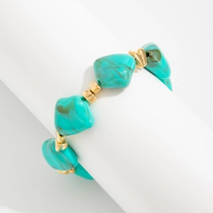 Detailed shot of irregular turquoise resin beads with gold spacers on a jewelry display