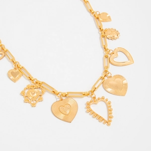 Detail of gold heart pendant chain with hollow design and textured relief on white background