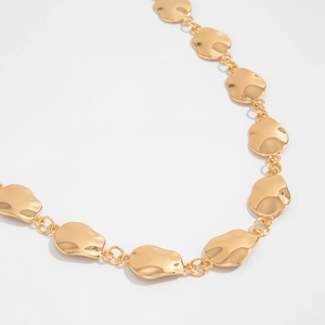 Detail of the minimalist gold waist chain showing smooth organic geometric link pieces
