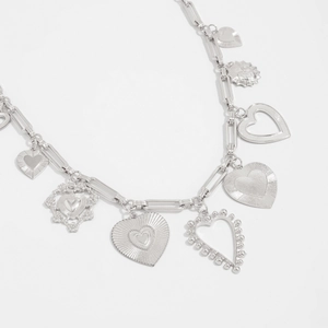 Close-up of silver paperclip chain featuring various engraved and hollow heart pendants