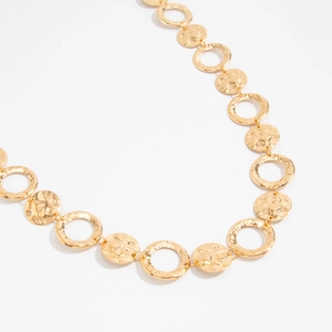 Detail of gold metal waist chain with hammered textured discs and smooth hollow rings