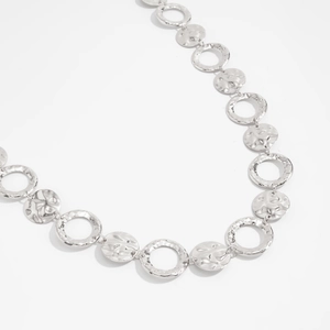 Detailed shot of silver geometric body chain with hollow rings and hammered metal discs
