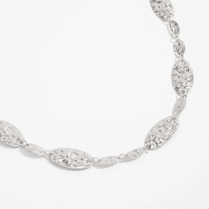 Detail of silver hammer textured oval links on a minimalist geometric metal body chain