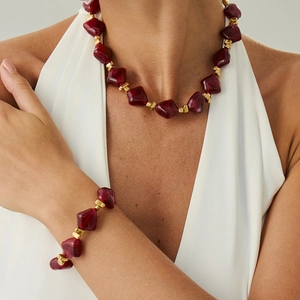 Irregular red resin beaded necklace and bracelet set with gold spacers on a model