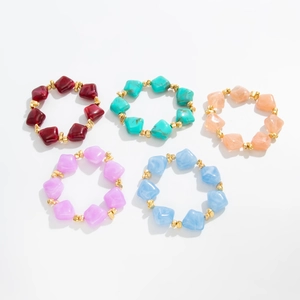 Five irregular resin bead rings in various colors with gold spacers on white background