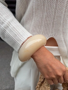 Close-up of a chunky cream resin bangle with a polished irregular minimalist design