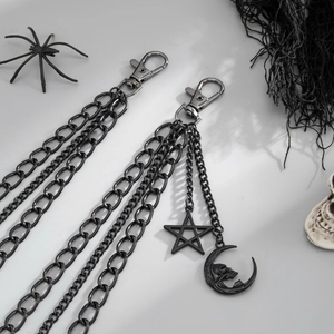 Vista macro della catena punk con maglie multistrato e ciondoli a forma di stella e luna