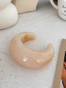 Macro detail of chunky cream resin cuff bracelet with marbled texture on stone surface