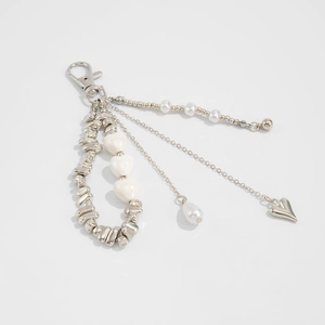 Detailed view of silver heart charms and irregular pearls on a stylish bag keychain