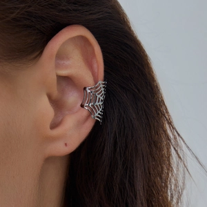 Macro detail van een donkere gotische spinnenweb oorklem op een model, punk metalen sieraad