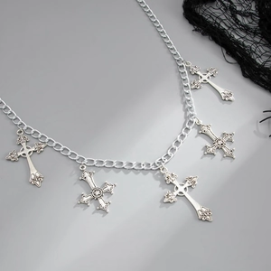 Macro detail of Gothic silver metal body chain with vintage cross pendants and dark layered chains