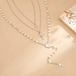 Detail van de meerlaagse zilveren kruisketting met kralen en een heilige medaille met reliëf