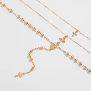 Detail van gelaagde gouden kettingen met kruishangers, kralen en een heilige medaille