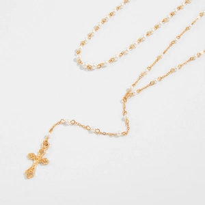 Detail van een vergulde rozenkrans ketting met witte parels en een kruis hanger