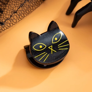 Vue détaillée de la pince à cheveux chat noir à paillettes avec yeux jaunes polis