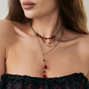 Détail d'un collier choker gothique avec triples chaînes noires et perles de cristal rouge